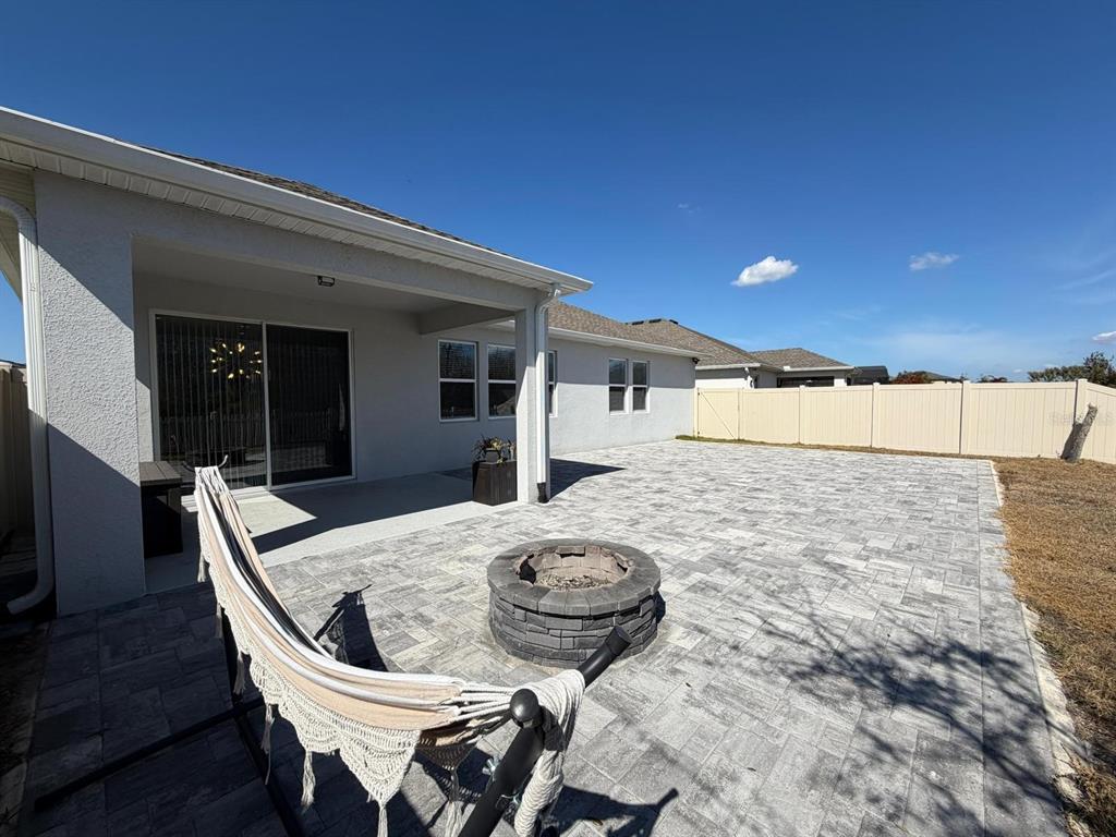 A backyard patio features a stone fire pit, a hammock, and a vinyl privacy fence — 3647 VEGA CREEK DRIVE, ST CLOUD, FL