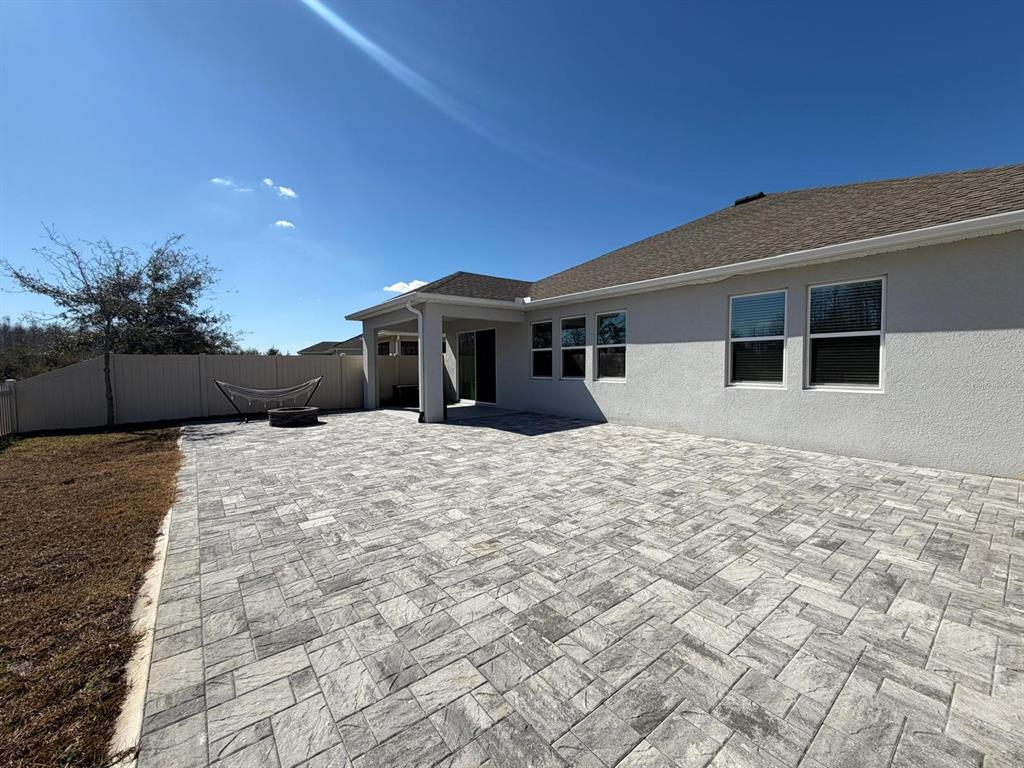 A backyard features a large gray paver patio, a covered lanai, and a vinyl fence — 3647 VEGA CREEK DRIVE, ST CLOUD, FL
