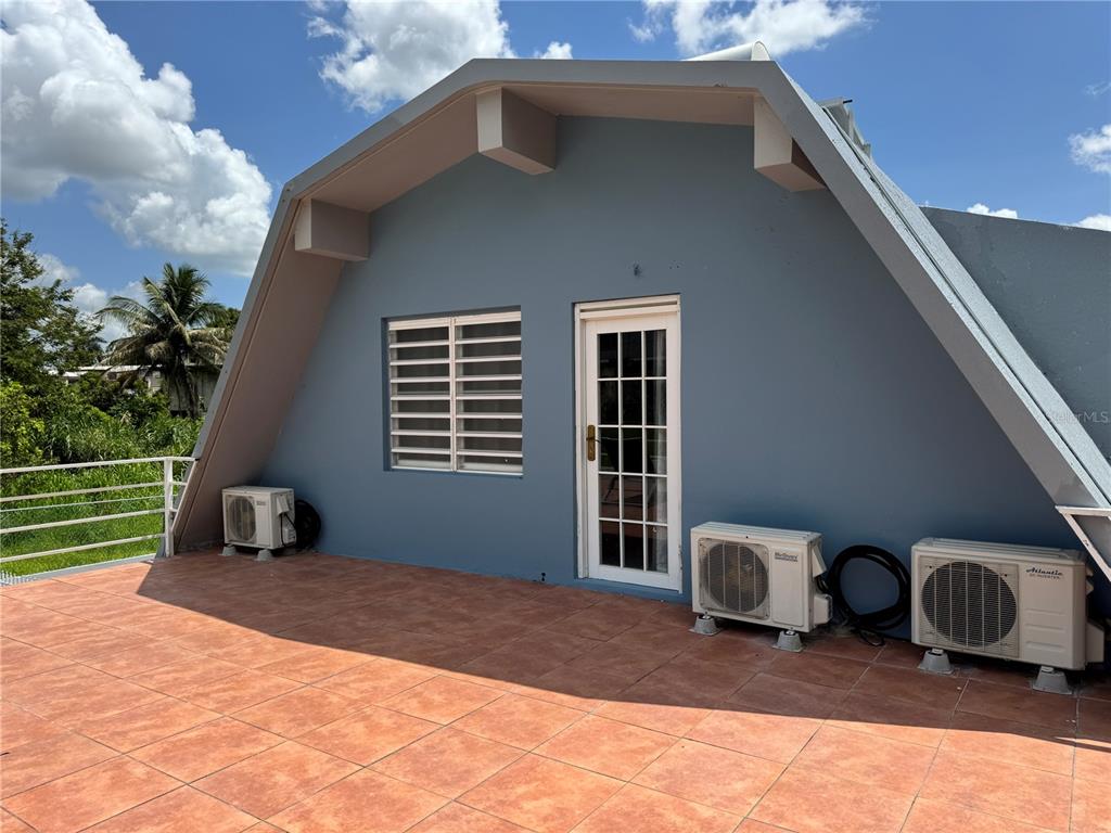 A tiled outdoor terrace features a blue exterior wall, a door, a window, and three air-conditioning units — 5 BO CELADA, GURABO, PR