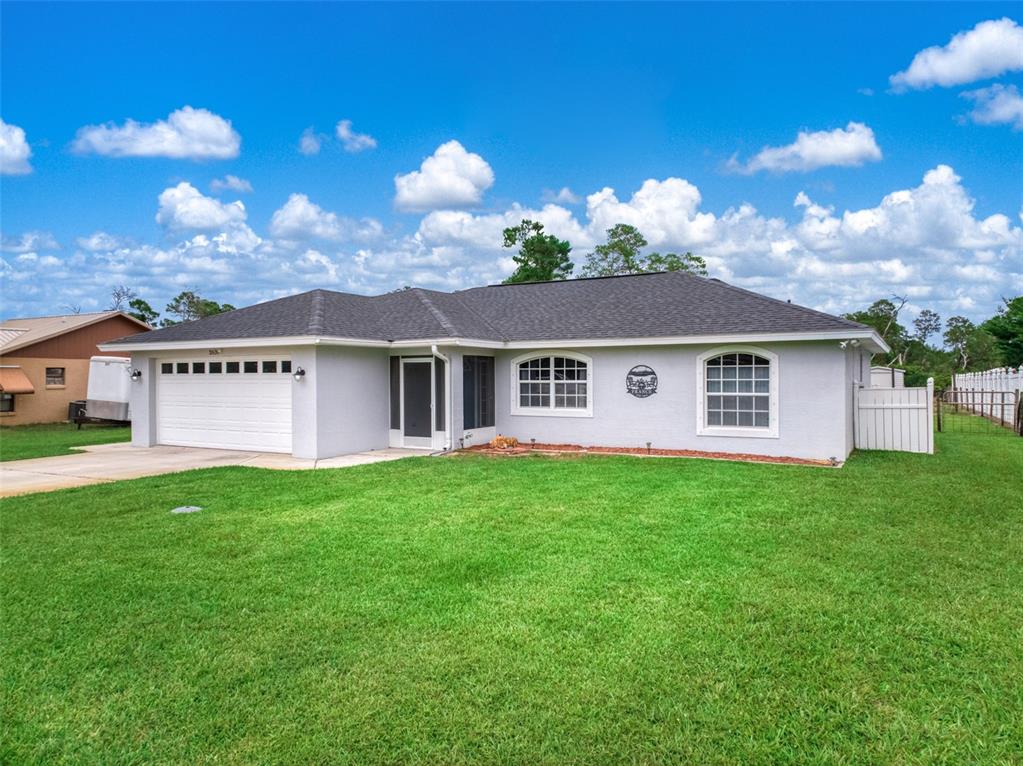 A single-story house with a white garage, gray exterior, and a large front lawn — 2630 GRESHAM STREET, SEBRING, FL