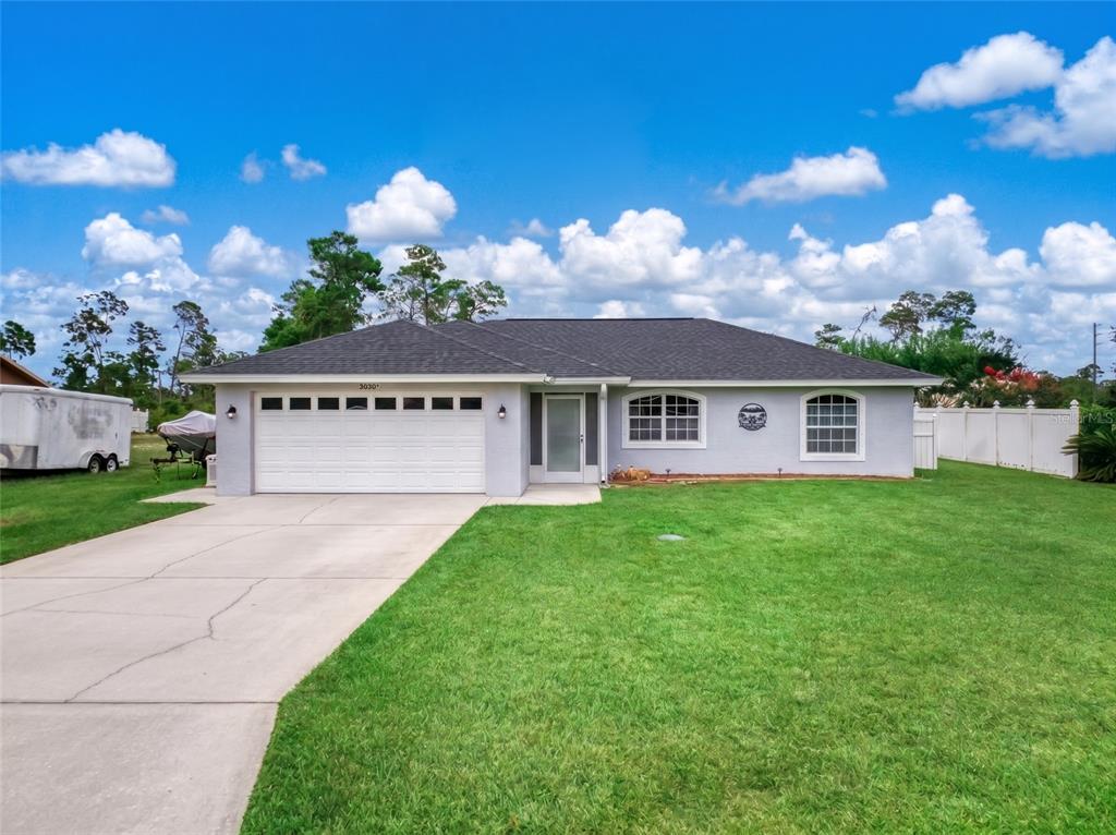 A single-story house with a white stucco exterior, a two-car garage, and a large lawn — 2630 GRESHAM STREET, SEBRING, FL