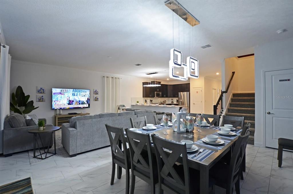 An open-concept living and dining area features tile floors, a gray sectional, and modern lighting — 4213 PARAGRAPH DRIVE, KISSIMMEE, FL