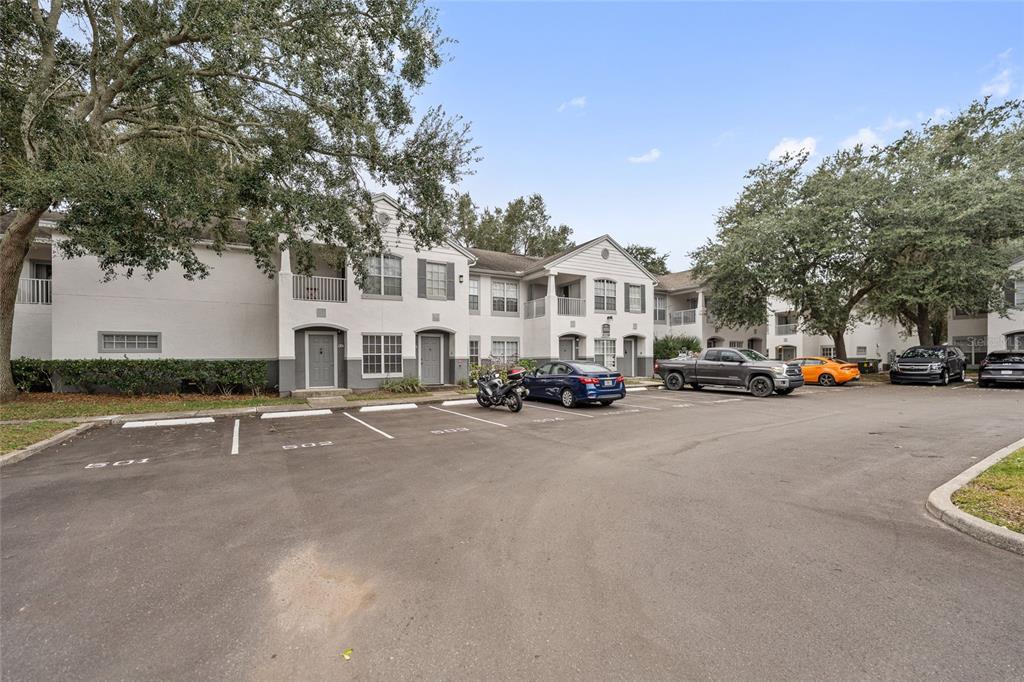 A two-story apartment building exterior with a paved parking lot in the foreground — 4356 S KIRKMAN ROAD UNIT 514, ORLANDO, FL