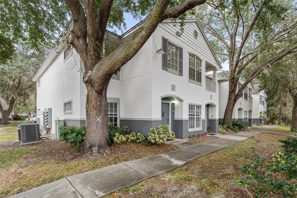 A two-story white and gray apartment building exterior with a large tree in the foreground — 4356 S KIRKMAN ROAD UNIT 514, ORLANDO, FL