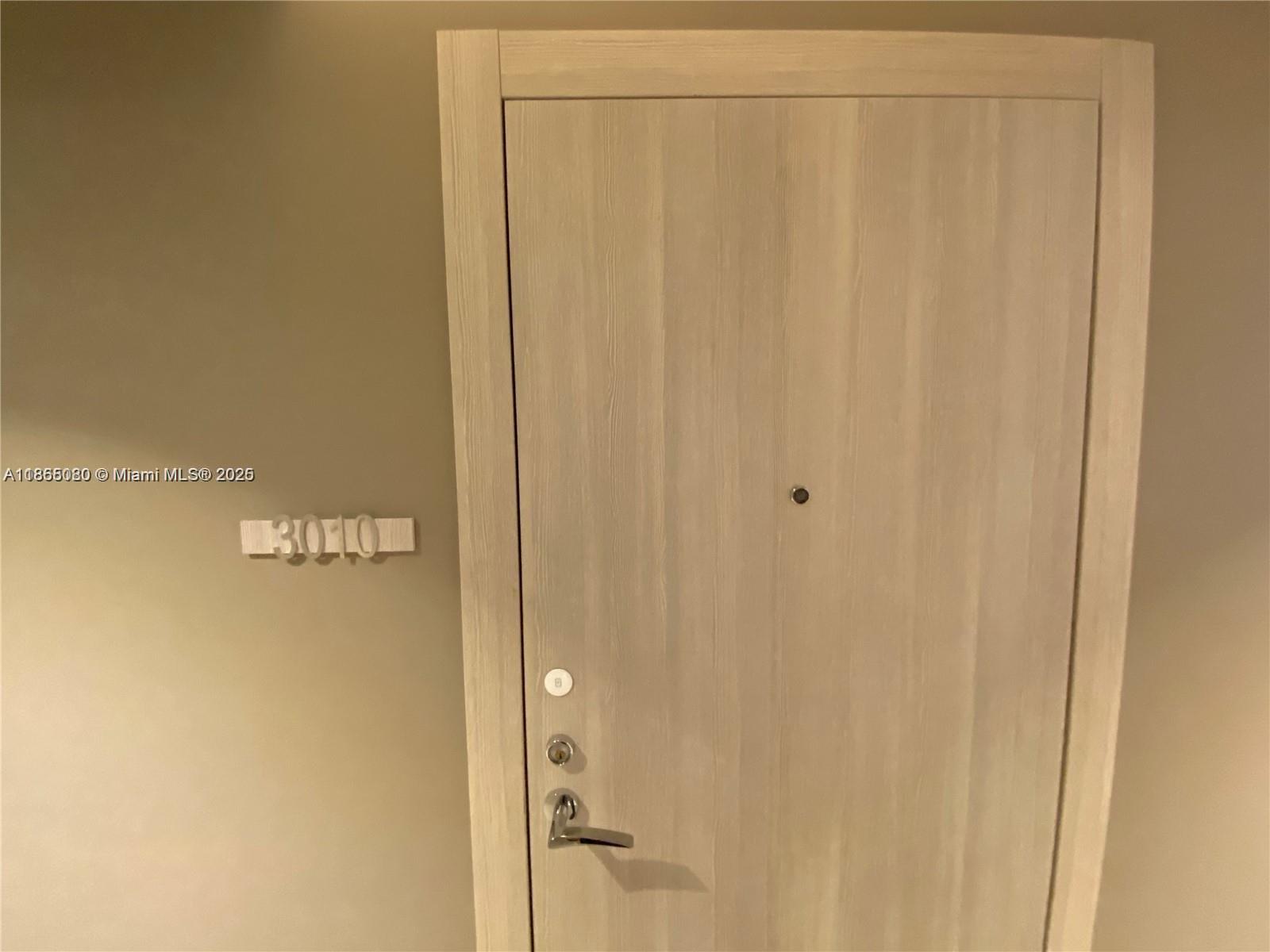 A light wood-grain door features a silver handle and the unit number 3010 — 1000 Brickell Plz # 3010, Miami FL 33131, MIAMI, FL