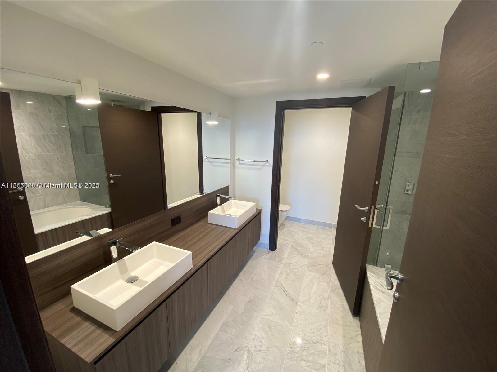 A modern bathroom features a double vanity with vessel sinks, marble flooring, and a shower — 1000 Brickell Plz # 3010, Miami FL 33131, MIAMI, FL