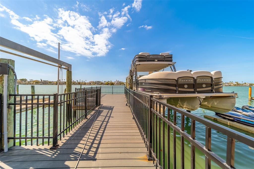 A wooden dock with black metal railings features a pontoon boat on a lift — 824 ISLAND WAY, CLEARWATER BEACH, FL