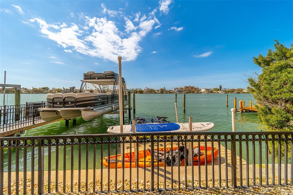 A pontoon boat, a kayak, and a paddleboard are docked at a waterfront pier — 824 ISLAND WAY, CLEARWATER BEACH, FL
