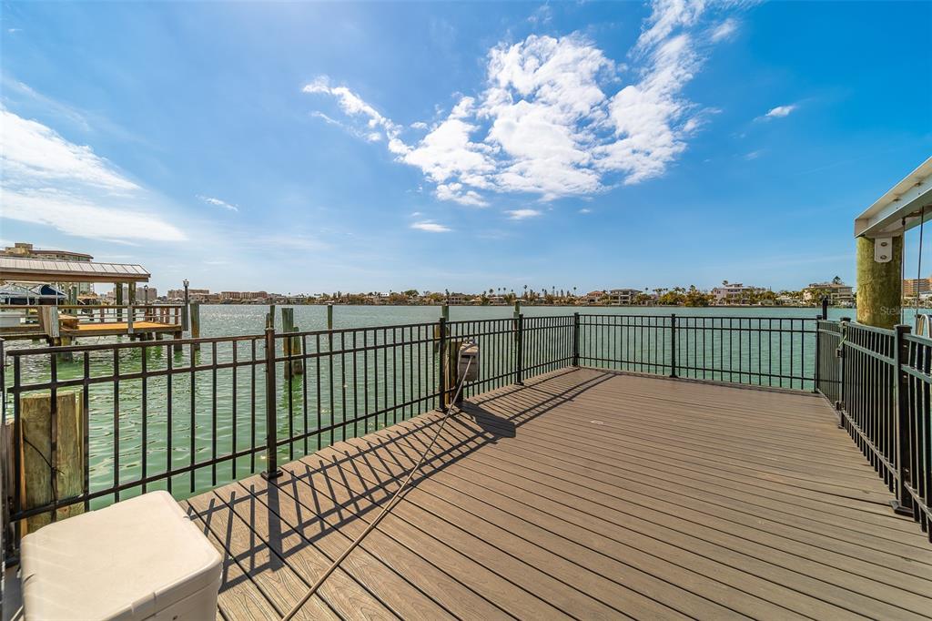 A wooden deck with black metal railings overlooks a body of water under a blue sky — 824 ISLAND WAY, CLEARWATER BEACH, FL