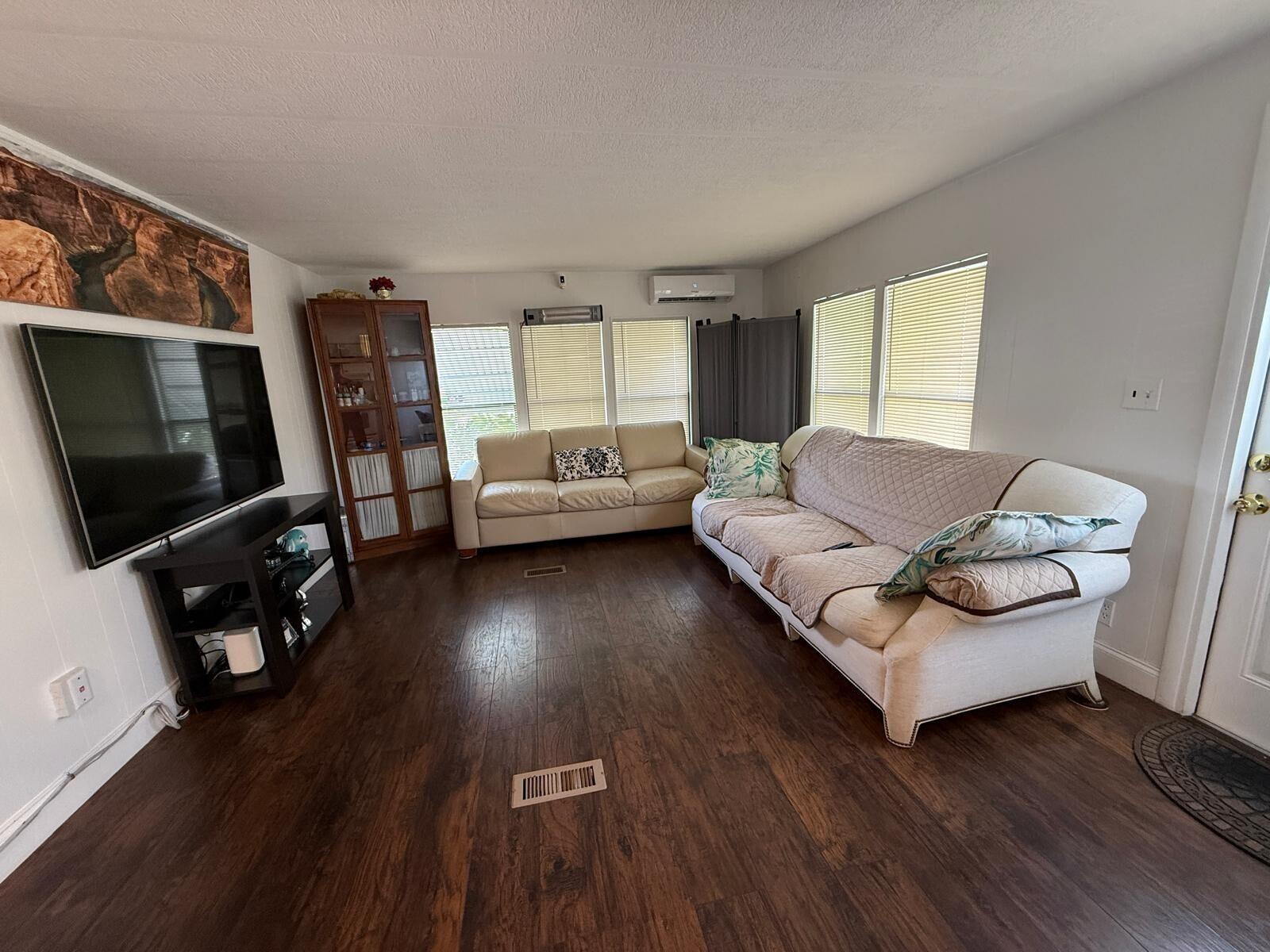 A living room features dark wood flooring, two sofas, a television, and a display cabinet — 3875 Sheraton Circle # 121, Boynton Beach FL 33436, BOYNTON BEACH, FL