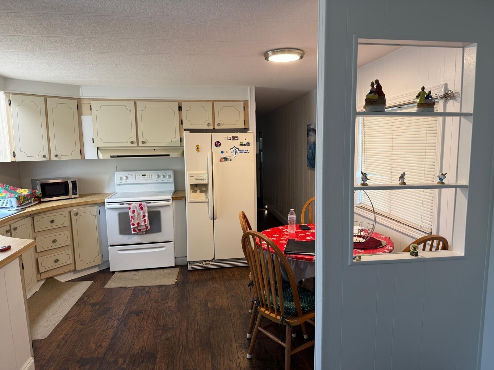 A kitchen with light-colored cabinets, white appliances, and a small dining area with wooden chairs — 3875 Sheraton Circle # 121, Boynton Beach FL 33436, BOYNTON BEACH, FL