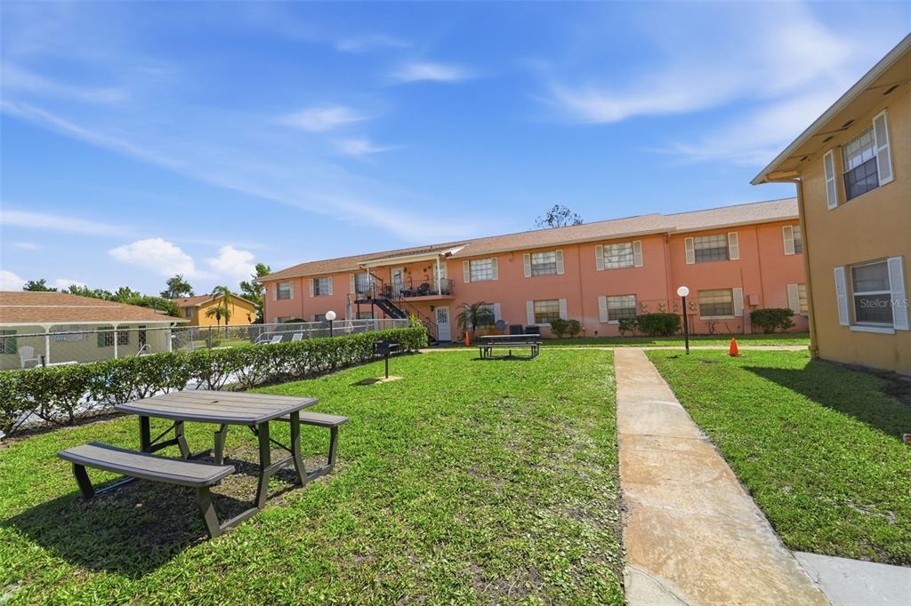 A grassy courtyard features two picnic tables and a sidewalk between two apartment buildings — 1655 W OAK RIDGE ROAD UNIT D, ORLANDO, FL