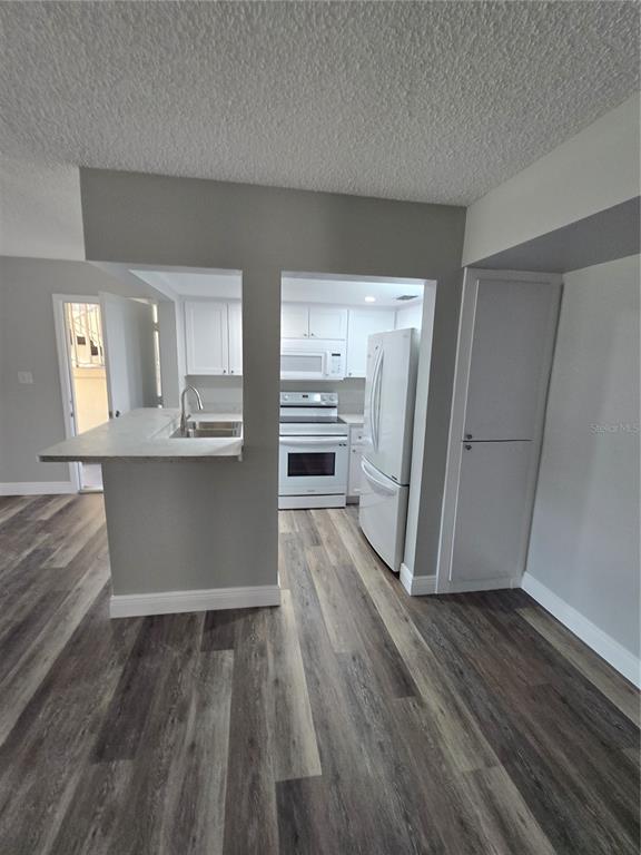 A kitchen with white cabinets, white appliances, and a breakfast bar overlooks a living area — 4600 MARINE PARKWAY UNIT 107, NEW PORT RICHEY, FL