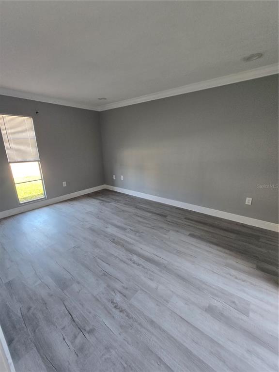 An empty room with gray walls, white trim, and light-colored wood-look flooring — 4600 MARINE PARKWAY UNIT 107, NEW PORT RICHEY, FL