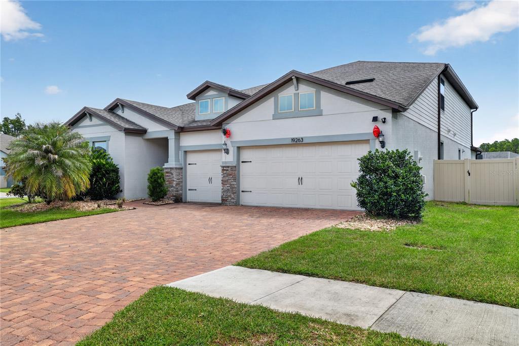 A two-story house with a three-car garage, stone accents, and a brick paver driveway — 19263 BRIARBROOK DRIVE, TAMPA, FL
