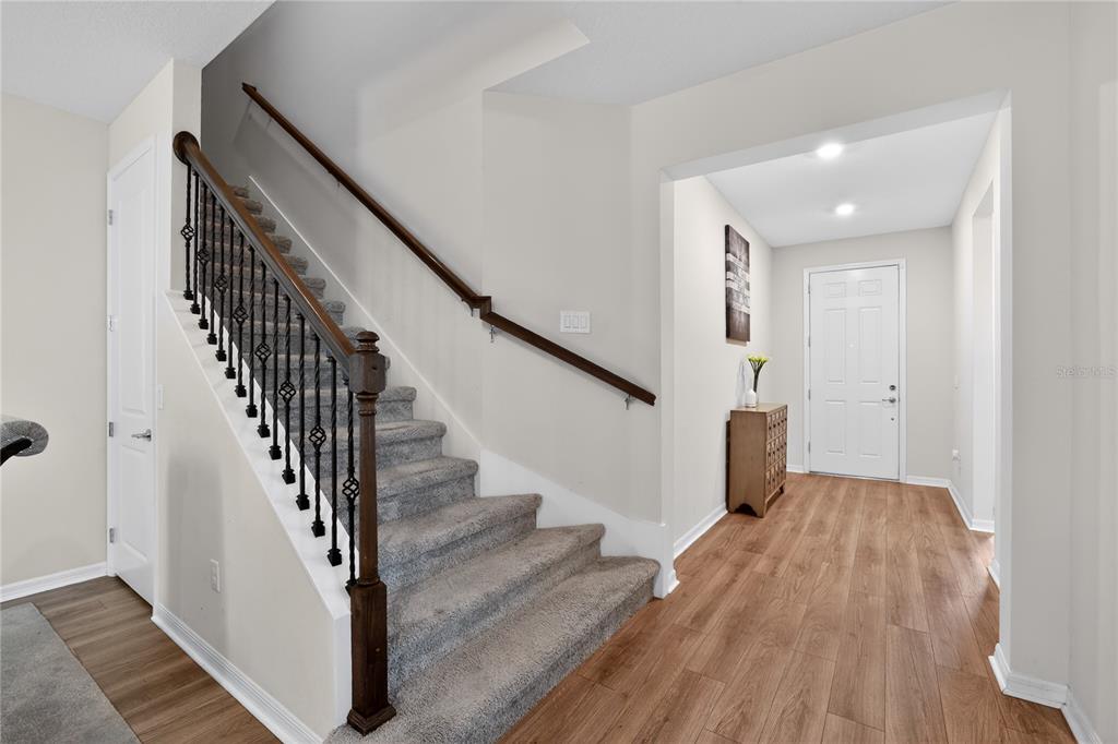 An entryway features a carpeted staircase with a wooden handrail and light wood flooring — 19263 BRIARBROOK DRIVE, TAMPA, FL