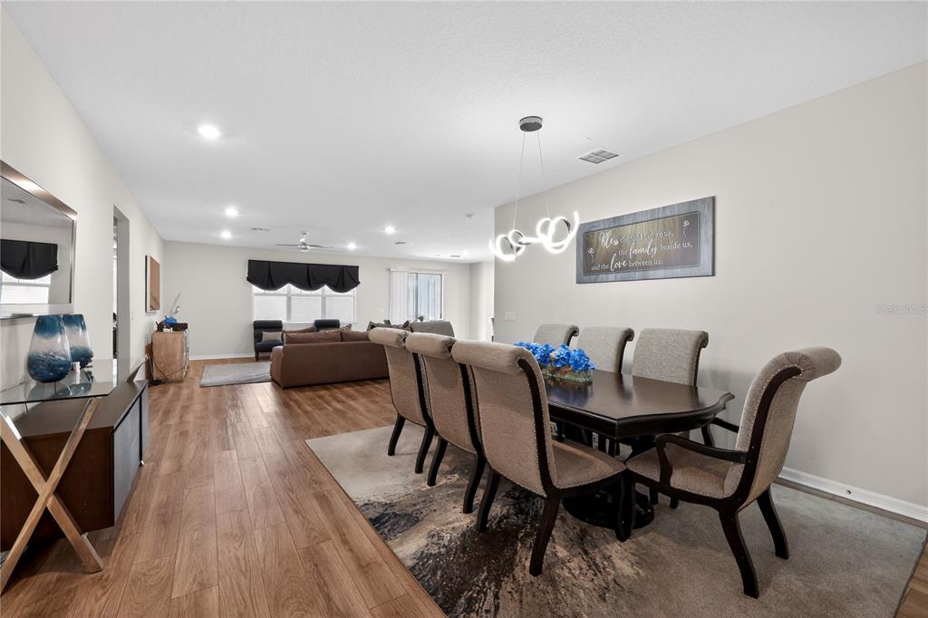 A dining area with a dark wood table and chairs sits adjacent to an open living room — 19263 BRIARBROOK DRIVE, TAMPA, FL