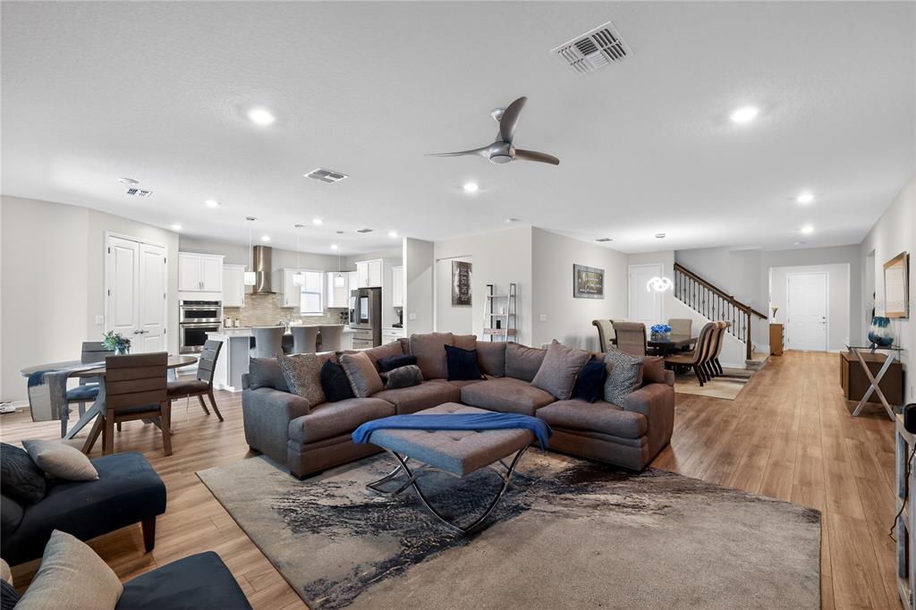 An open-concept living room features a sectional sofa, dining area, and kitchen with wood flooring — 19263 BRIARBROOK DRIVE, TAMPA, FL