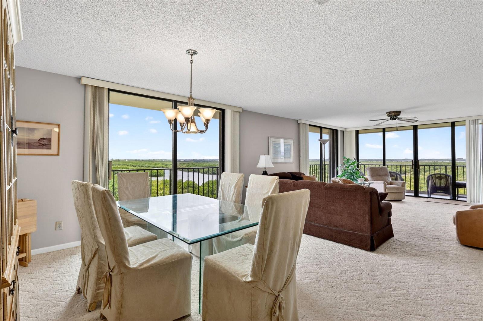 A dining area with a glass table and chairs opens into a living room with views — FORT PIERCE, FL