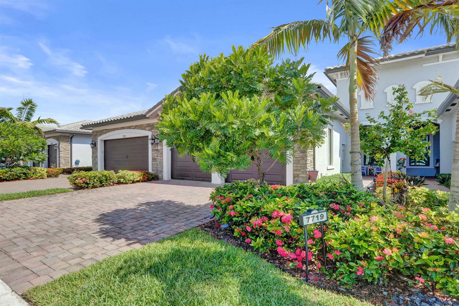 A residential house exterior features a paved driveway, a two-car garage, and landscaped flower beds — 7719 S Blue Spring Drive, Parkland FL 33067, PARKLAND, FL