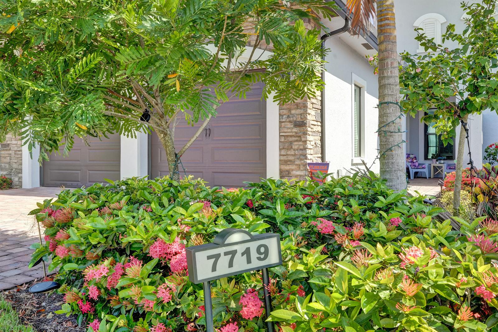 A house exterior features a two-car garage, stone accents, and a landscaped front yard — 7719 S Blue Spring Drive, Parkland FL 33067, PARKLAND, FL