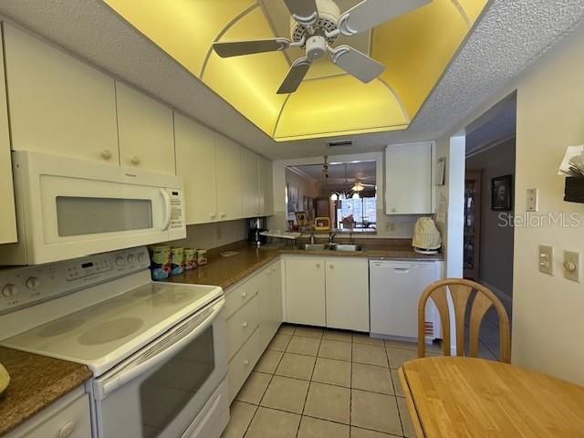 A kitchen features white cabinetry, a white stove, a ceiling fan, and tiled flooring — 2664 WOODGATE LANE UNIT D2, SARASOTA, FL