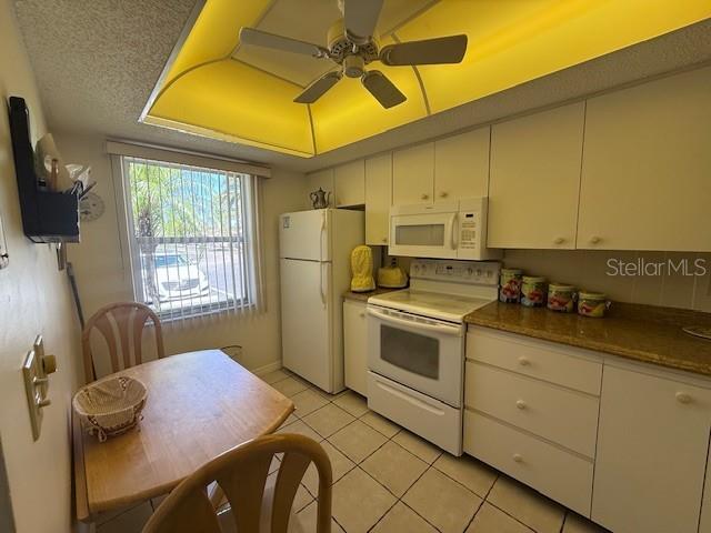 A kitchen features white cabinets, a white refrigerator, a white stove, and a small dining table — 2664 WOODGATE LANE UNIT D2, SARASOTA, FL