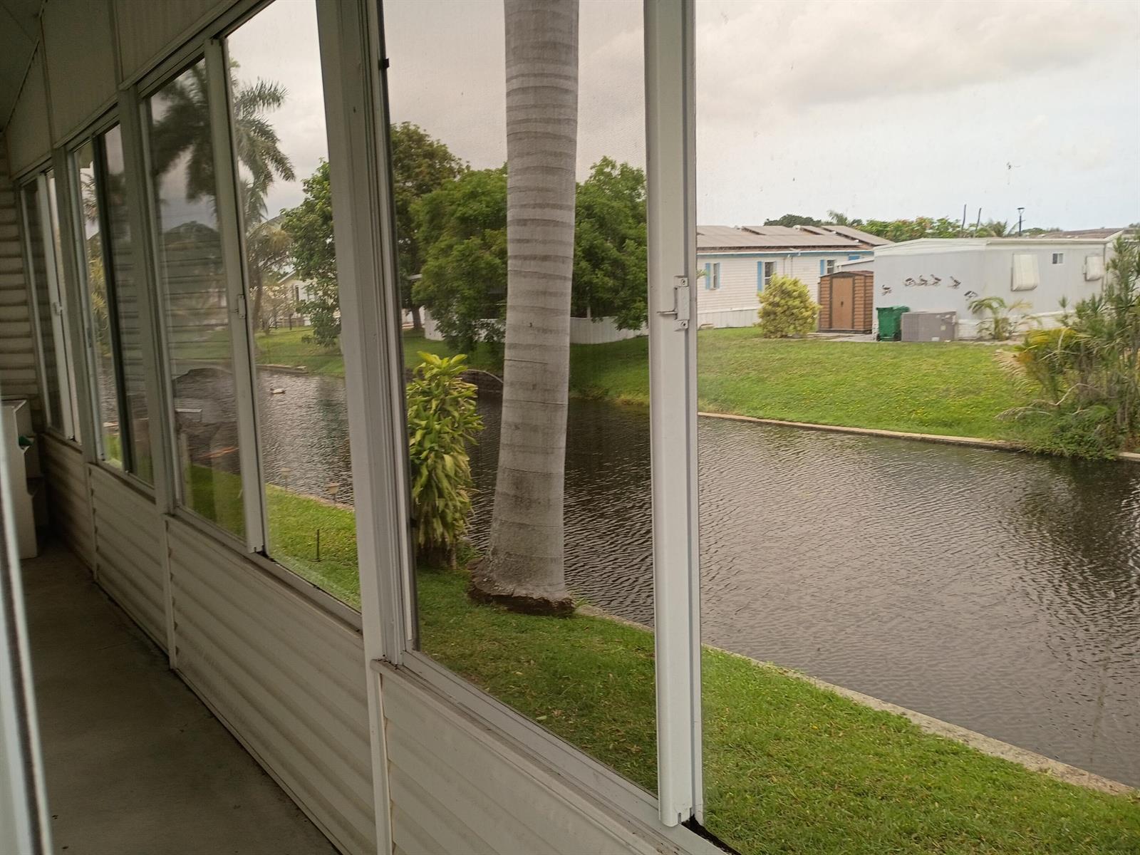 A view of a canal and neighboring houses from a screened-in porch — 2080 SW 85th Avenue, Davie FL 33324, DAVIE, FL