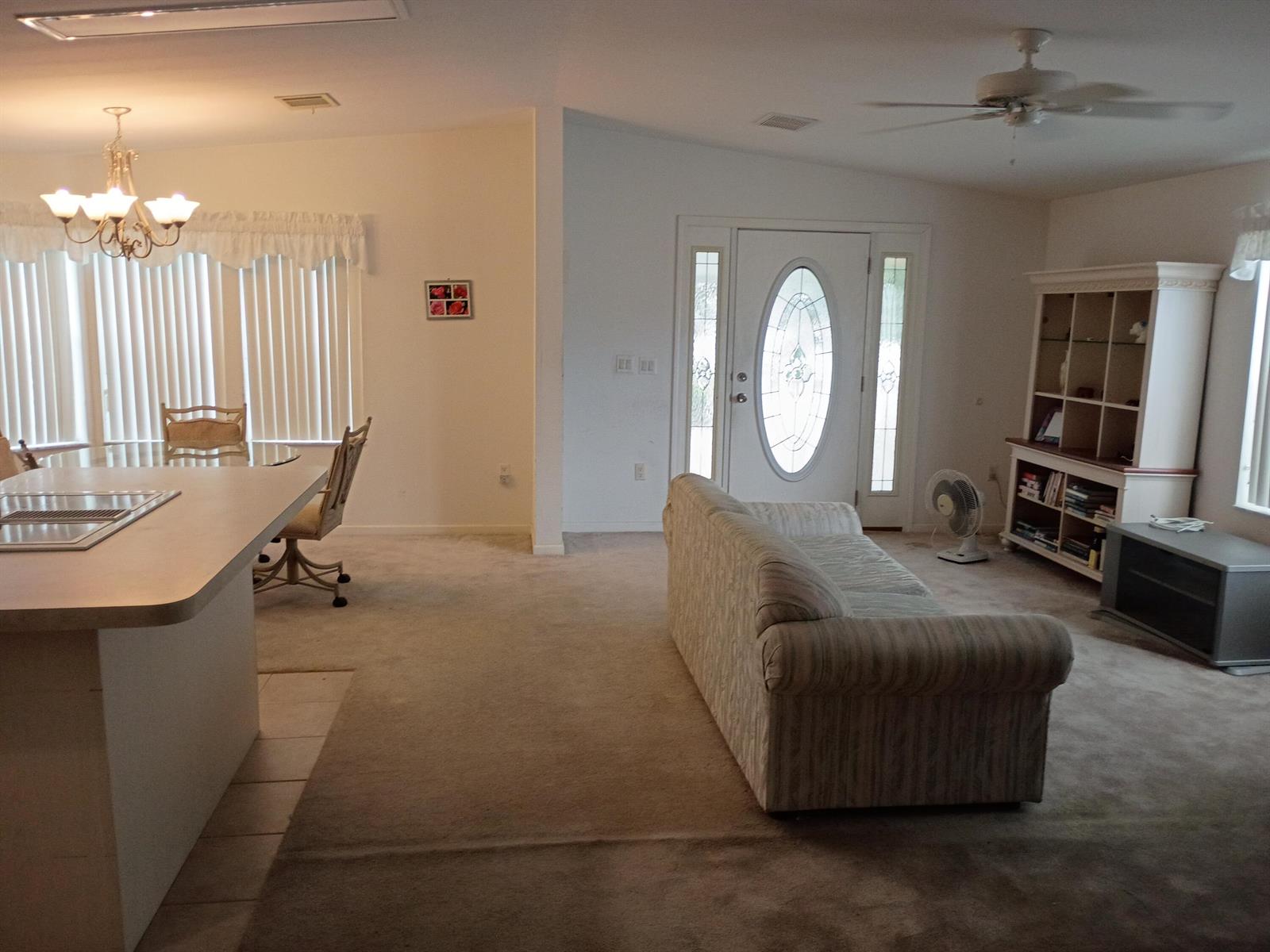An open-concept living and dining area features a kitchen island, carpeted floors, and a sofa — 2080 SW 85th Avenue, Davie FL 33324, DAVIE, FL