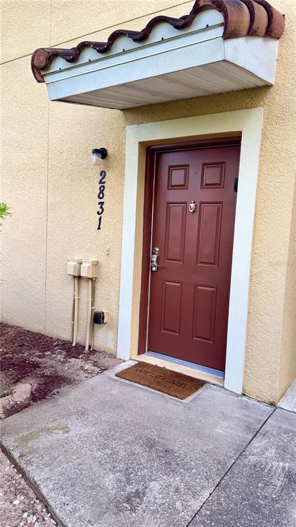 A red front door with a small awning and house number 2831 on the wall — 2831 OAKWATER DRIVE UNIT 2831, KISSIMMEE, FL