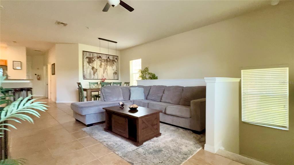 A living room with a gray sectional sofa, a wooden coffee table, and a dining area — 2831 OAKWATER DRIVE UNIT 2831, KISSIMMEE, FL