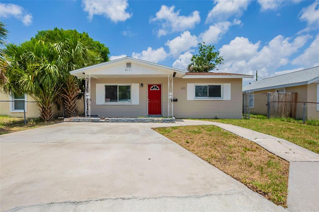 A single-story house with a red front door, concrete driveway, and a large palm tree — 4111 13TH AVENUE S, ST PETERSBURG, FL