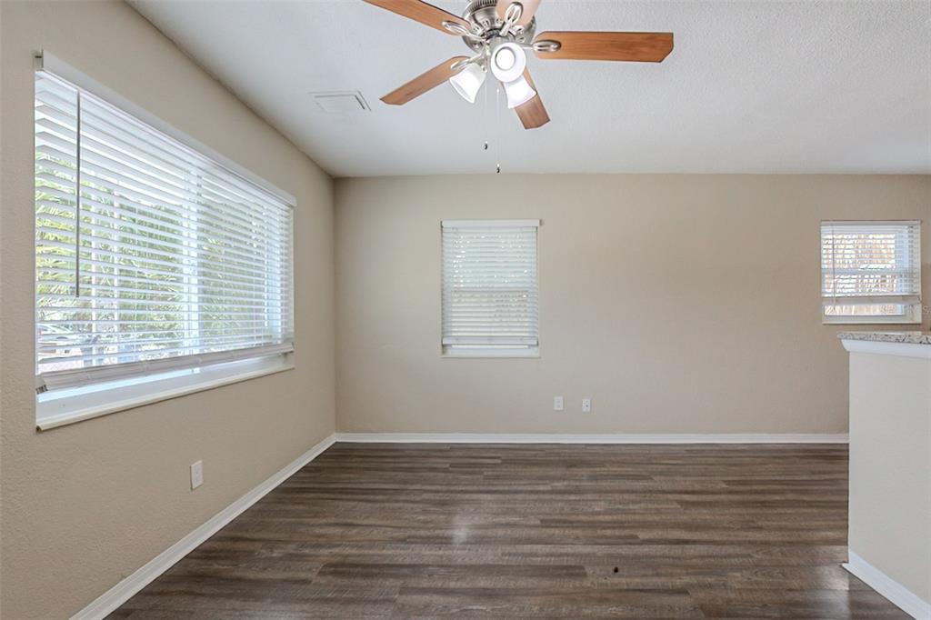 An empty room with wood-look flooring, a ceiling fan, and windows with white blinds — 4111 13TH AVENUE S, ST PETERSBURG, FL