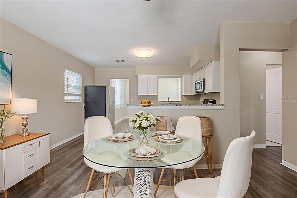 A dining area with a glass table and chairs sits in front of a kitchen — 4111 13TH AVENUE S, ST PETERSBURG, FL