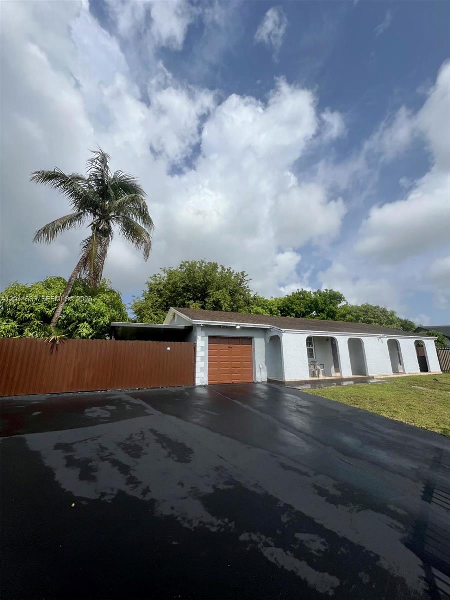 A single-story house with a brown garage door, a covered porch, and a paved driveway — 26080 SW 132nd Pl, Homestead FL 33032, HOMESTEAD, FL
