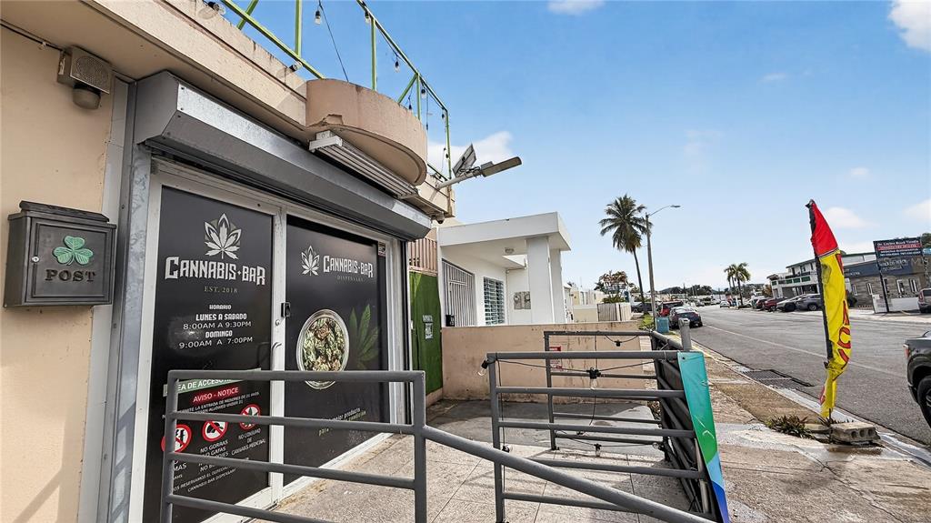 The exterior of a cannabis dispensary building features a storefront entrance and a metal railing — Urb. La Rosaleda EA10 AVE. BOULEVARD MONROIG, TOA BAJA, PR