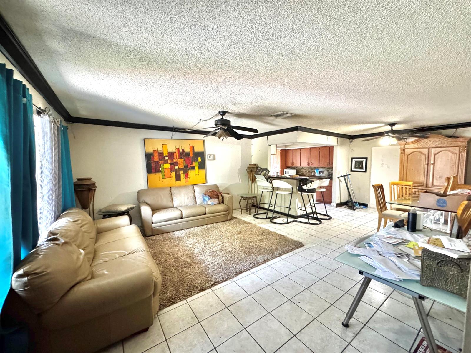A living room and kitchen area features tile floors, a popcorn ceiling, and two sofas — 4310 NE 1st Terrace, Pompano Beach FL 33064, POMPANO BEACH, FL