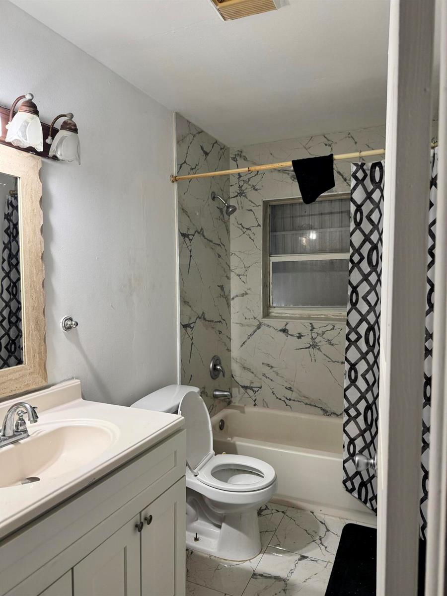 A bathroom features a vanity, toilet, and a bathtub with marble-patterned tile surround — 4310 NE 1st Terrace, Pompano Beach FL 33064, POMPANO BEACH, FL