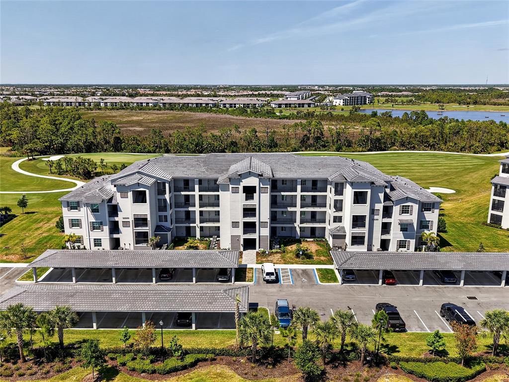 An aerial view shows a multi-story apartment building with covered parking and surrounding golf course grounds — 12320 WELLEN GOLF STREET UNIT 306, VENICE, FL