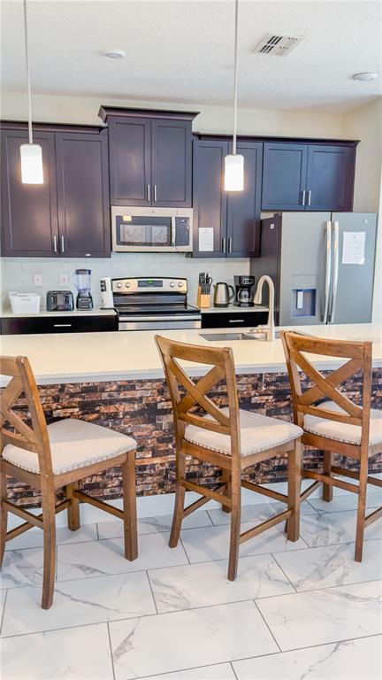 A kitchen features dark cabinets, a stone-tiled island base, and three wooden bar stools — 444 OCEAN COURSE AVENUE, DAVENPORT, FL