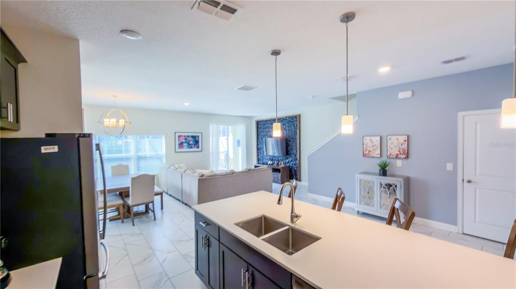 A kitchen island with a double sink overlooks an open-concept living and dining area — 444 OCEAN COURSE AVENUE, DAVENPORT, FL