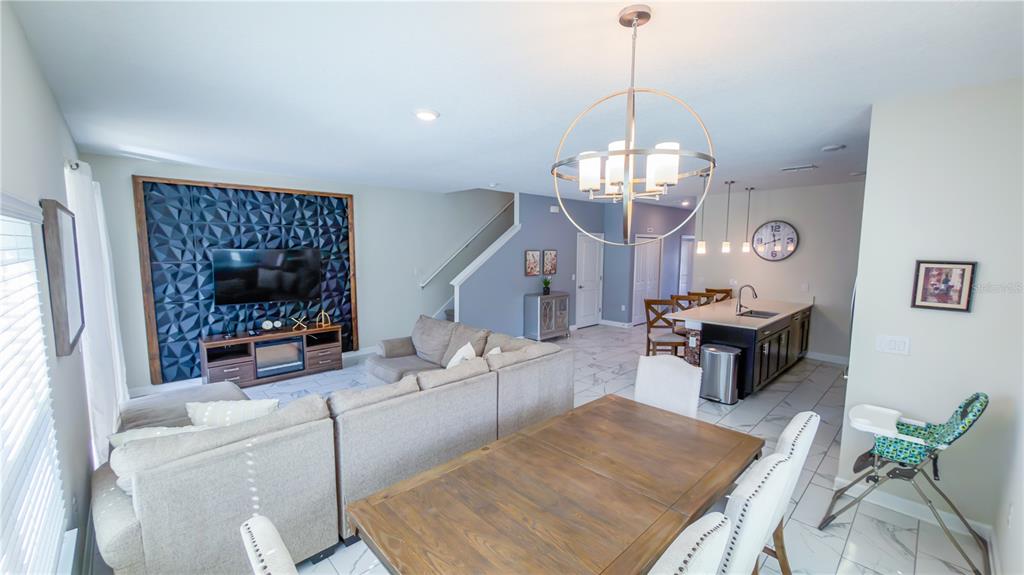 An open-concept living and dining area features a textured accent wall, tile flooring, and island — 444 OCEAN COURSE AVENUE, DAVENPORT, FL