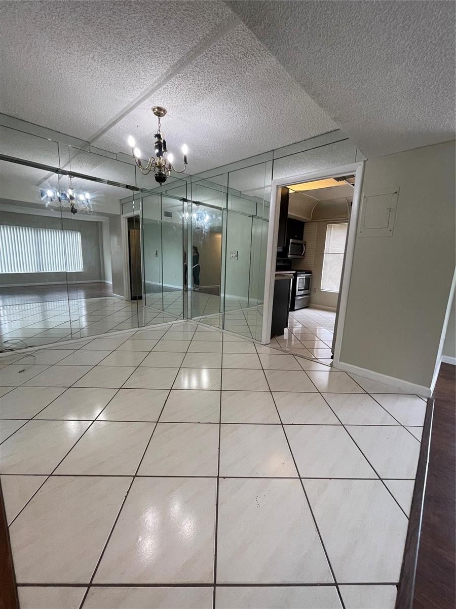 A tiled dining area features a mirrored wall and a chandelier, with a kitchen doorway — 4158 Inverrary Drive # 111, Lauderhill FL 33319, LAUDERHILL, FL