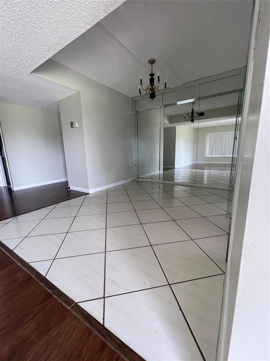 A dining area features white diamond-patterned tile flooring, a chandelier, and a mirrored wall — 4158 Inverrary Drive # 111, Lauderhill FL 33319, LAUDERHILL, FL