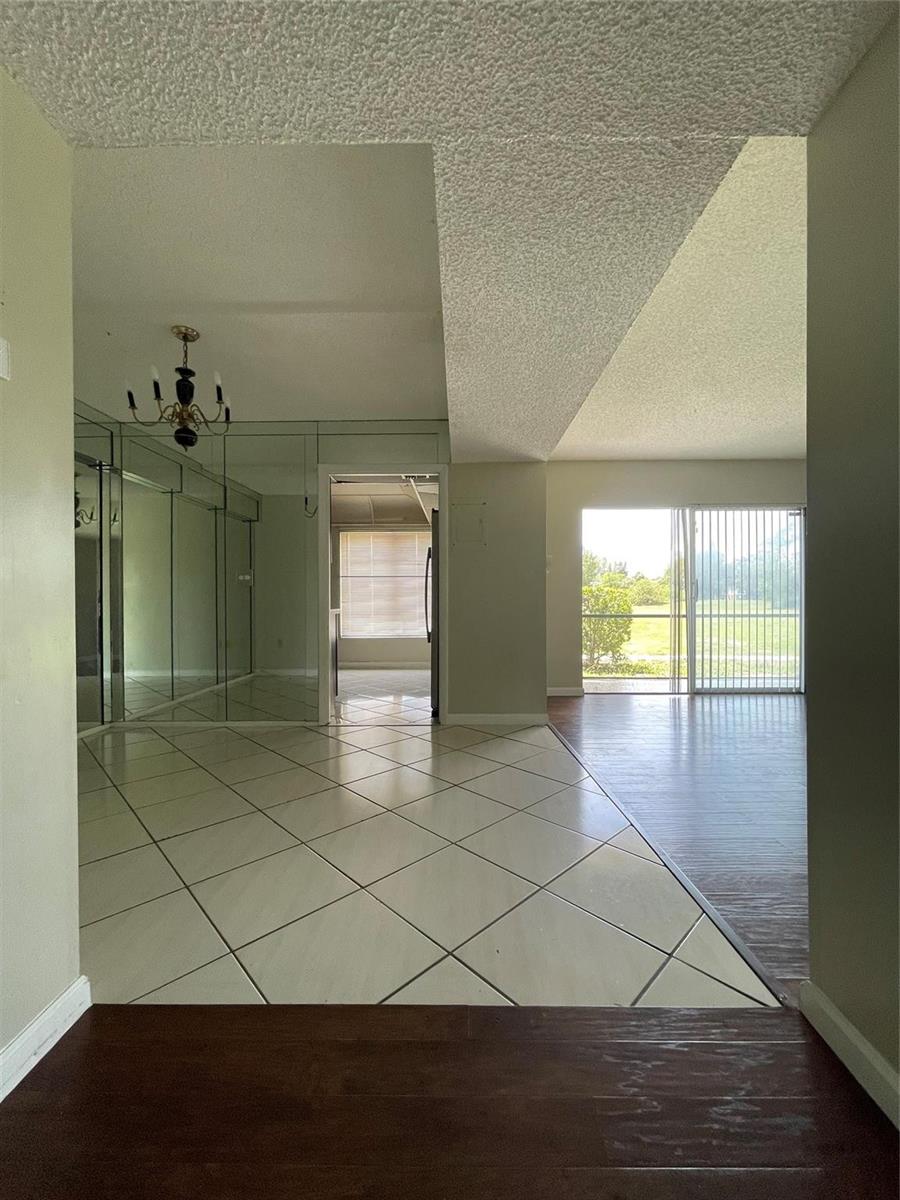 A view from a doorway showing a tiled entryway, mirrored walls, and a living area — 4158 Inverrary Drive # 111, Lauderhill FL 33319, LAUDERHILL, FL