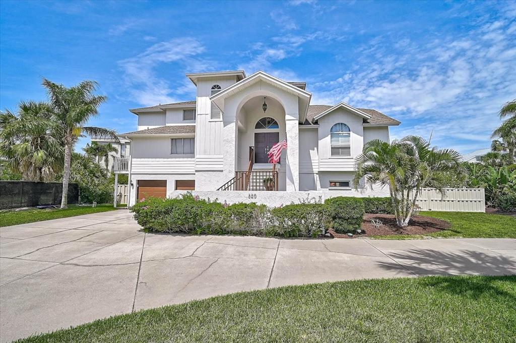 A two-story white house with a concrete driveway and palm trees in the front yard — 320 RINGLING POINT DRIVE, SARASOTA, FL