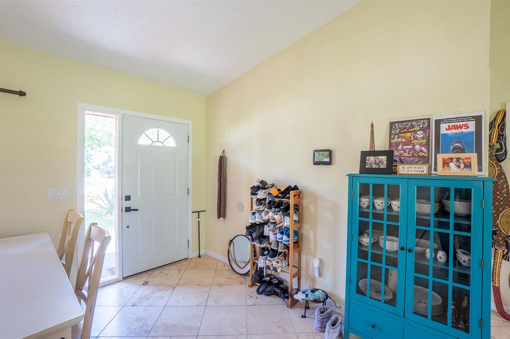 An entryway features tile flooring, a white front door, a shoe rack, and a blue cabinet — 25 ETHAN ALLEN DRIVE, PALM COAST, FL