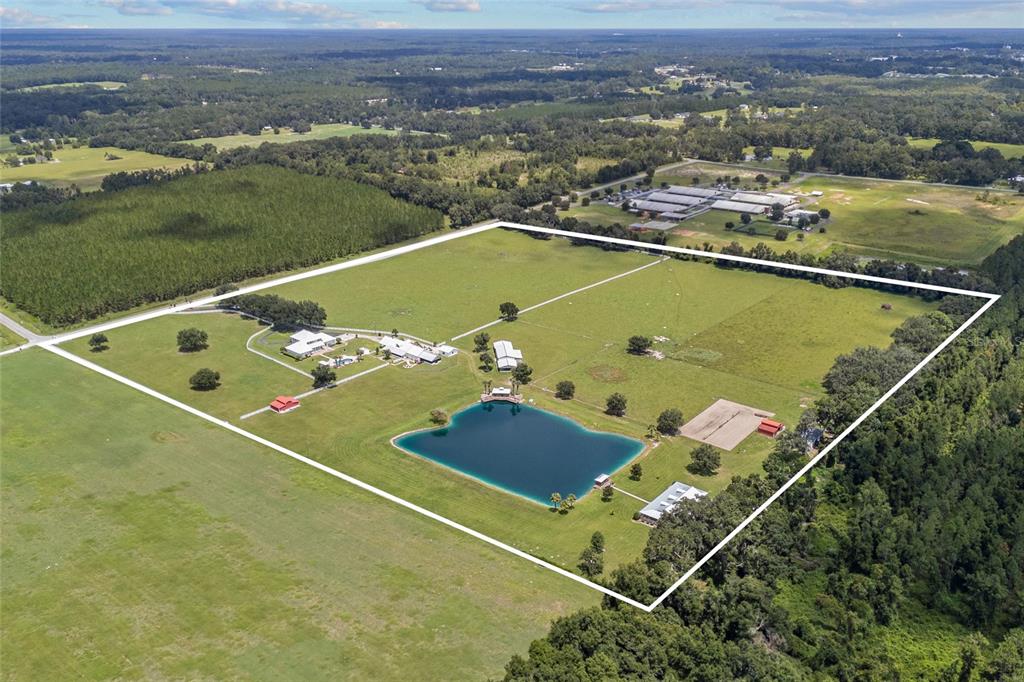 An aerial view shows a large rural property with a pond, buildings, and fenced pastures — 550 SW GABRIEL PLACE, LAKE CITY, FL