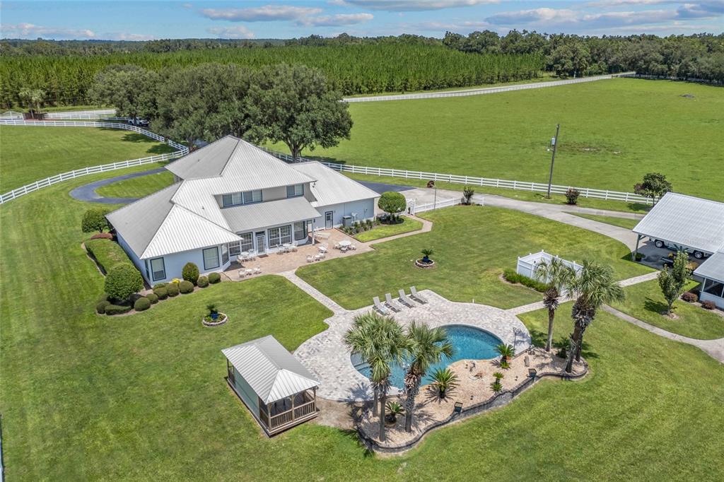 An aerial view shows a large house with a metal roof, pool, and detached garage — 550 SW GABRIEL PLACE, LAKE CITY, FL