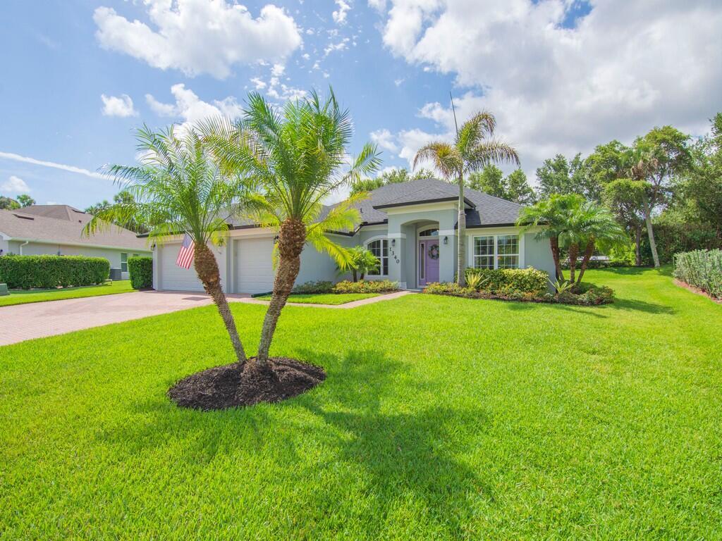 A single-story house with a light-colored exterior, a two-car garage, and palm trees in front — 1340 Willow Oak Court, Vero Beach FL 32966, VERO BEACH, FL